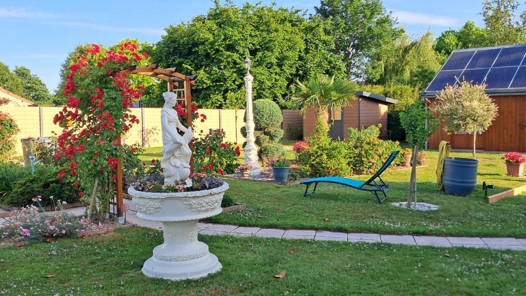 Jardin avec pergola de roses et statue